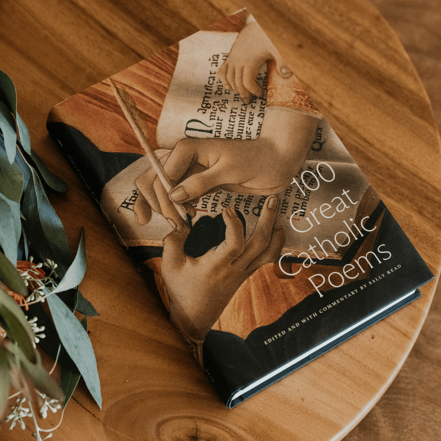 100 Great Catholic Poems book with a cover illustration of hands writing on parchment, edited by Sally Read, book of Catholic poetry, Word on Fire, hardcover 9781685780746