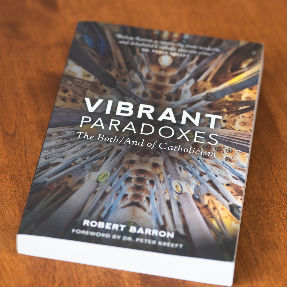 Vibrant Paradoxes: The Both/And of Catholicism book lying on a wooden surface, authored by Robert Barron with a foreword by Dr. Peter Kreeft, showcasing a colorful architectural ceiling design, books on Catholicism, paperback 9781943243105