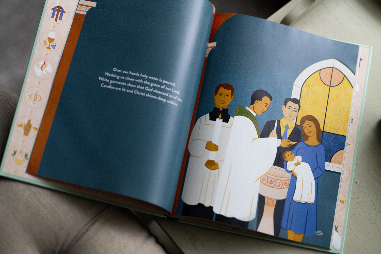 Open children's book showing an illustration of a baptism ceremony with a priest, parents, and baby in a church setting