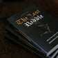 Stack of books titled 'The Last Riddle' on a dark surface